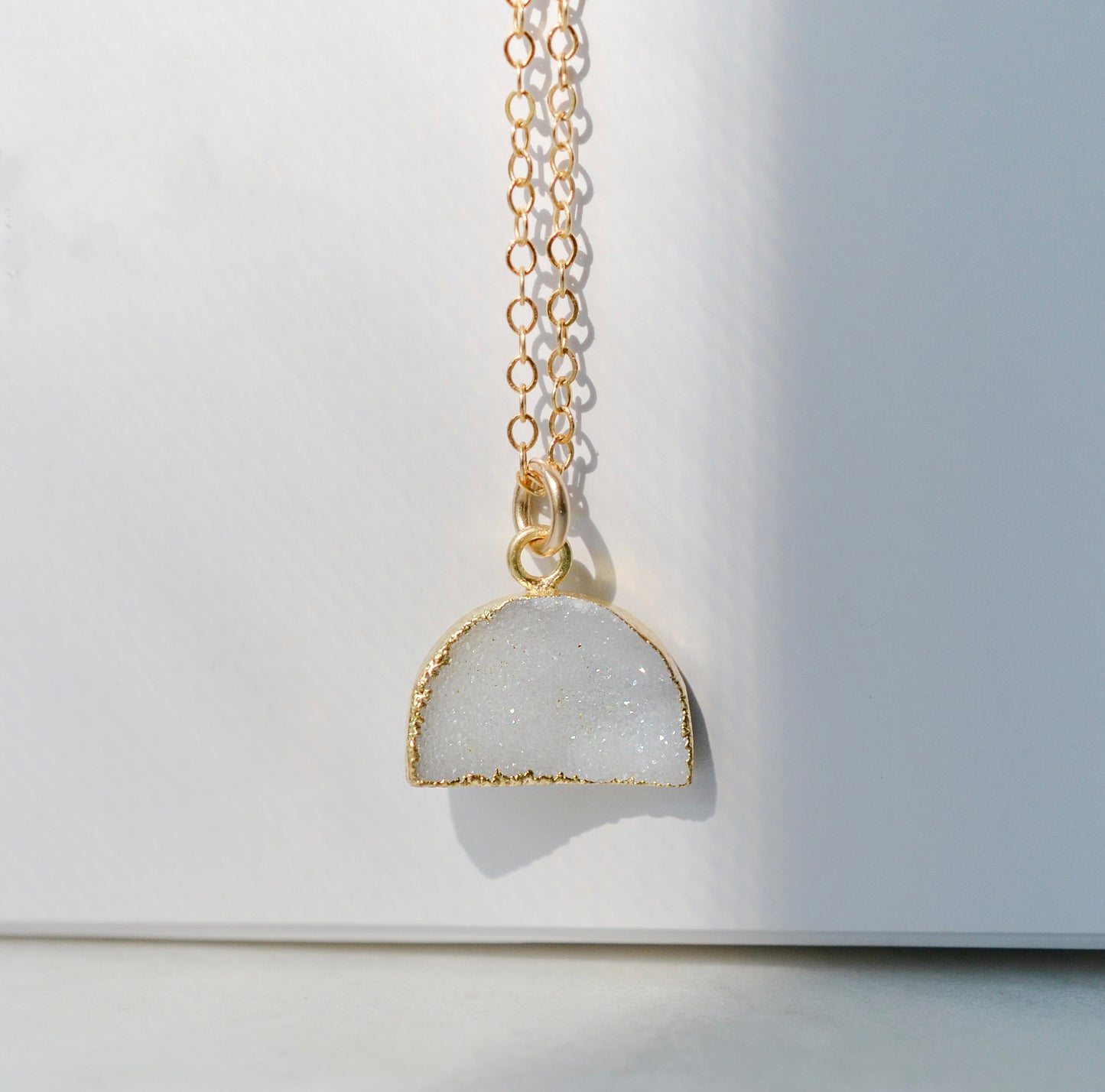 This necklace is handmade with a natural white druzy quartz pendant in a half-circle or crescent shape. Available in 14k gold filled.