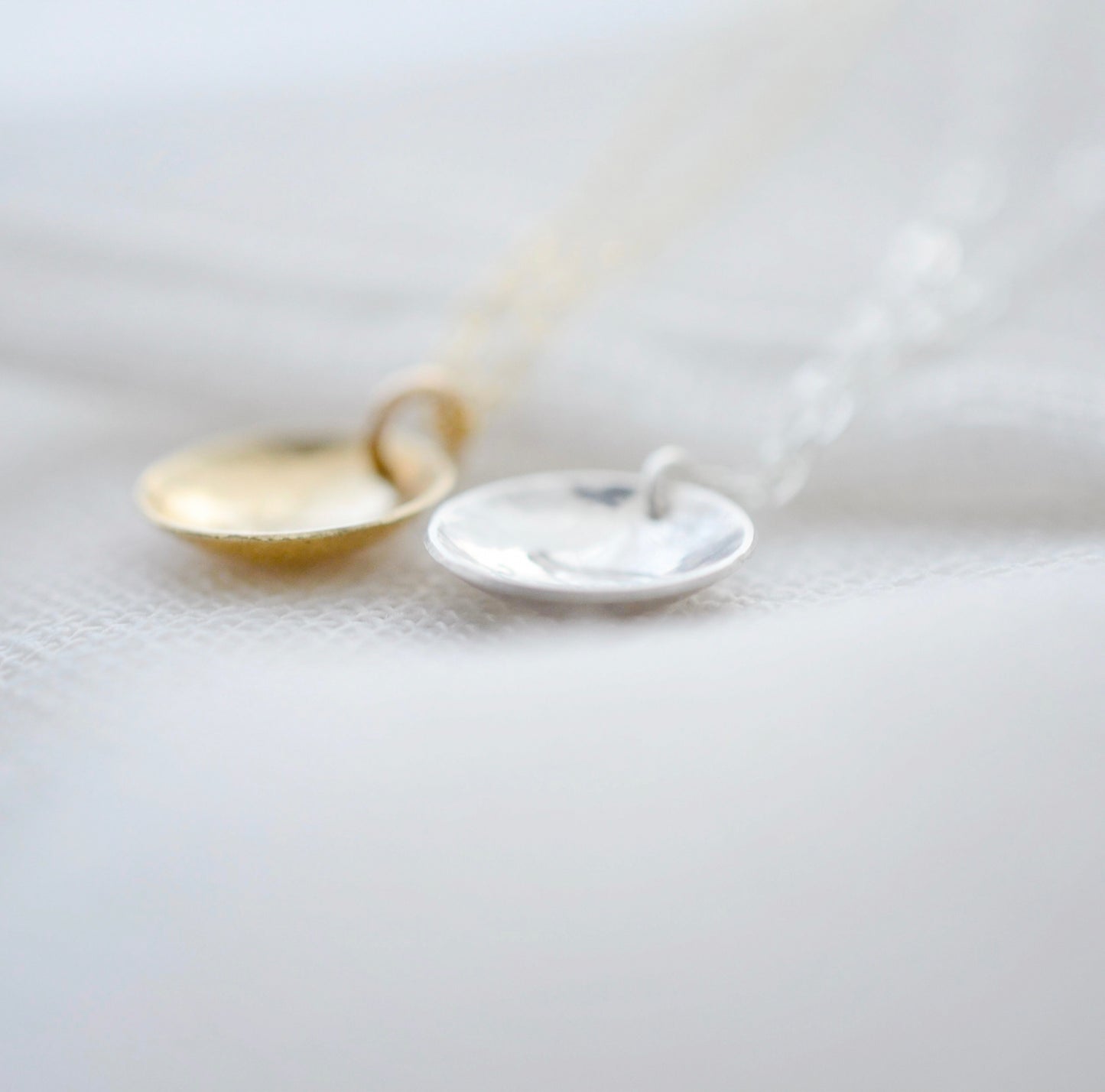 Om symbol stamped into a circle disc and put on a gold filled chain. Side view of gold and sterling silver options