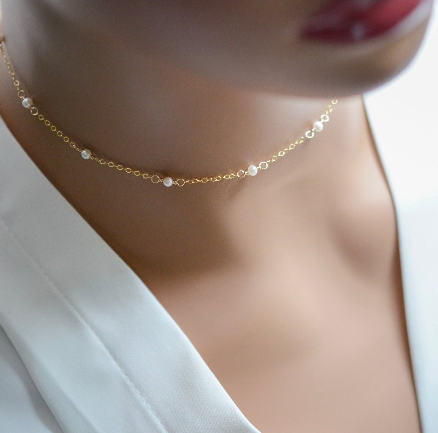 Modeled image of the natural white freshwater pearl chain necklace. Tiny freshwater pearls are mixed within a dainty cable chain in gold. Also available in sterling silver.