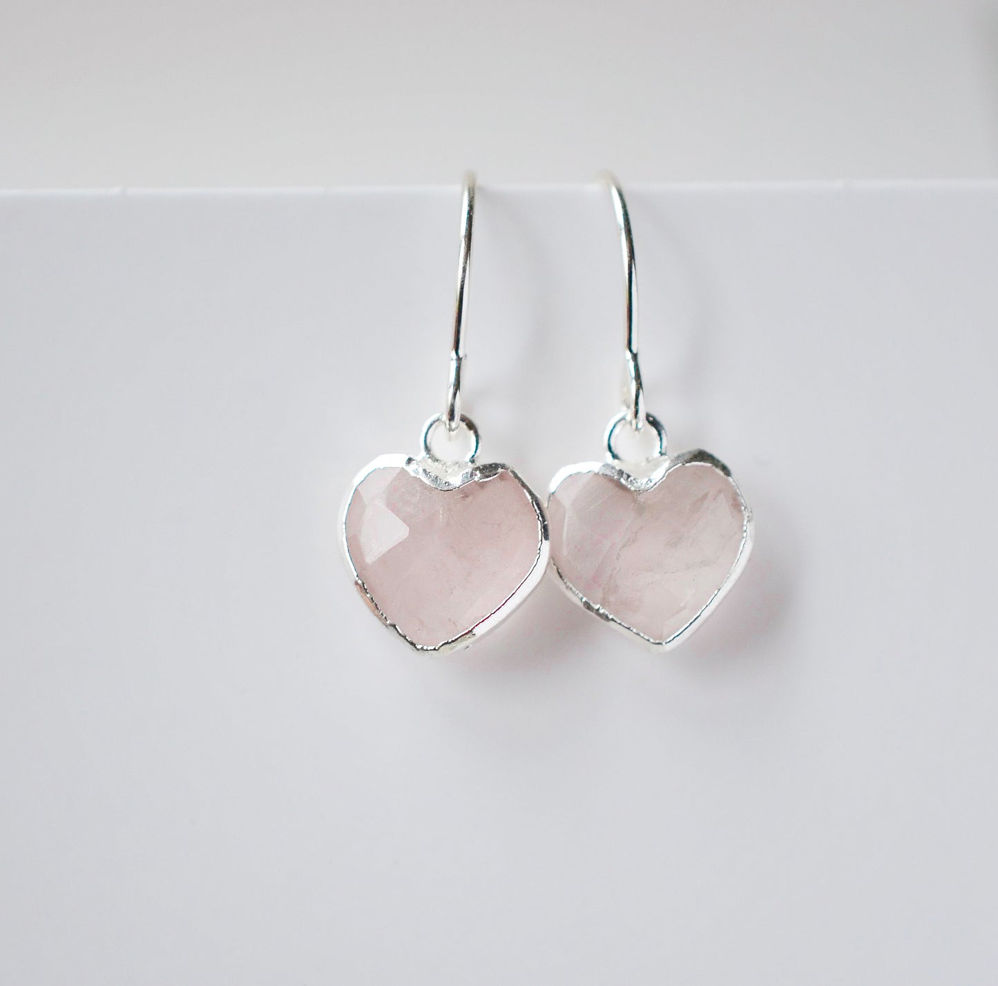 Minimalist, handmade rose quartz heart earrings featuring a faceted, sparkling heart—the stone of universal love. These cute dangles, approximately 0.5 inches (12mm/1.2cm) in size, are shown in sterling silver and are also available in 14k gold filled. They make a sweet and thoughtful gift for mom, daughter, niece, valentines day, or anniversary.