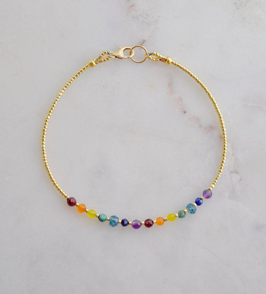 A beaded rainbow bracelet with natural crystal gemstones in the order of the chakras. This gold piece is handmade in Connecticut by Gemnia Jewelry.