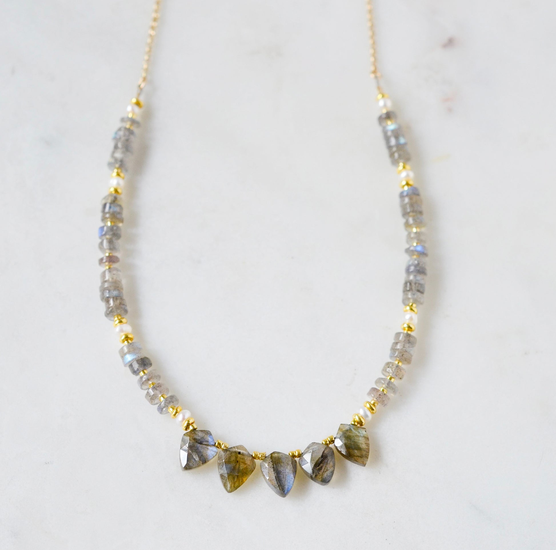 A handmade, beaded labradorite and pearl gemstone necklace with five labradorite teardrops in the front. Shown in 14k gold filled.