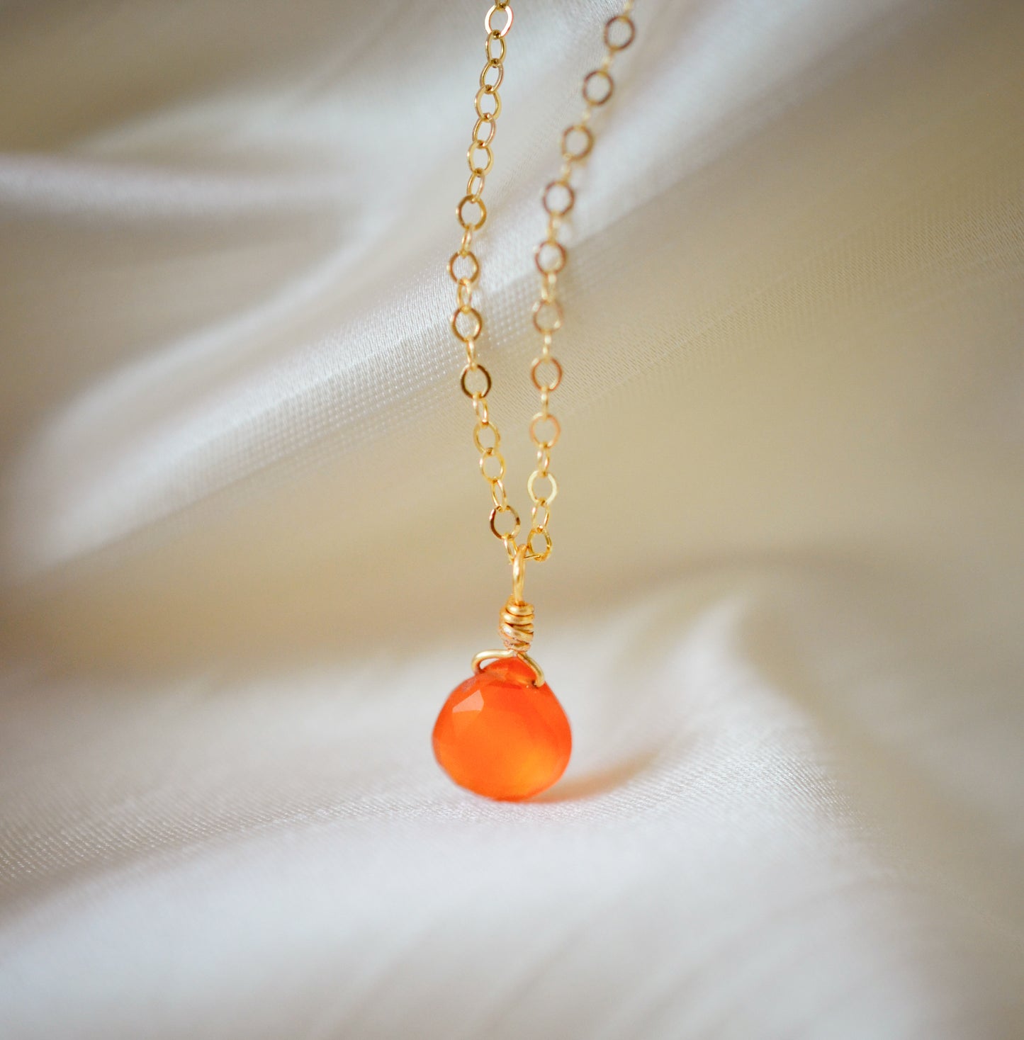 A small, natural orange Carnelian gemstone teardrop pendant suspended from a 14k gold filled cable chain. This necklace is handmade and also comes in sterling silver.