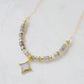 A beaded labradorite gemstone necklace with a white quartz druzy north star pendant at its center. Shown in gold.