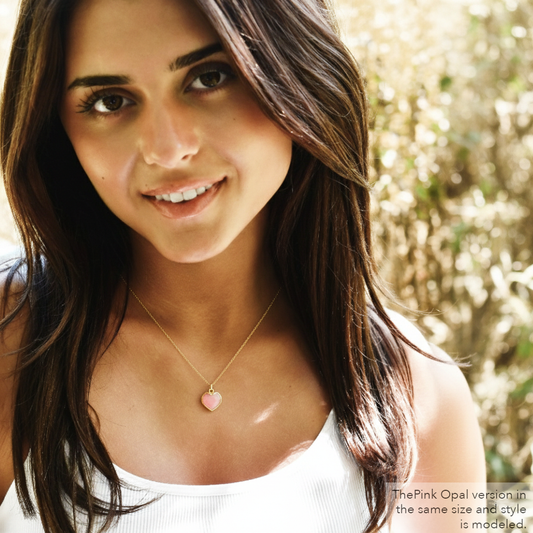Woman wearing a necklace with a pink heart pendant. Shown in pink opal.