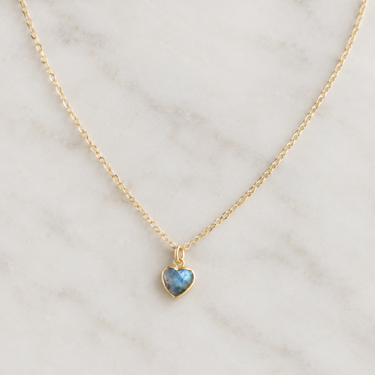 A delicate 14k gold filled chain necklace with a small heart-shaped pendant featuring a shimmering blue-gray natural labradorite gemstone. Handmade minimalist stone jewelry by Gemnia.