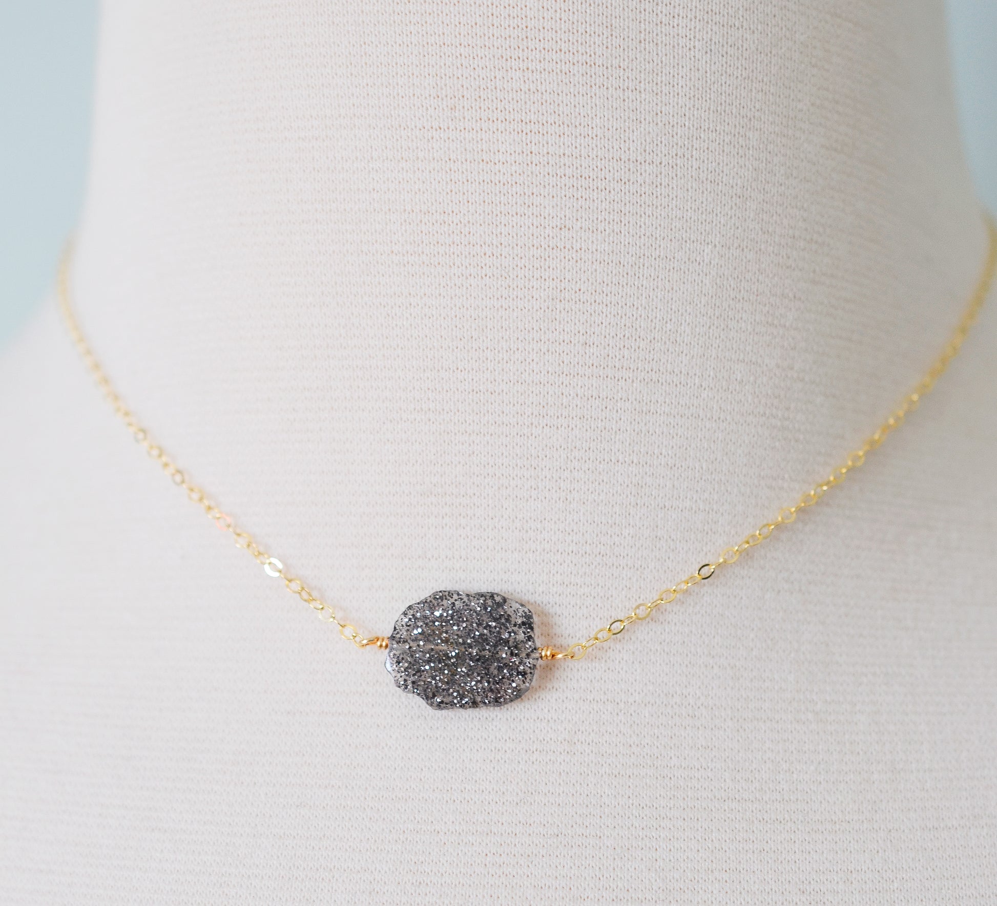 Genuine raw black sunstone gemstone set on a gold filled chain. The shape of the stone is irregular.
