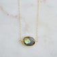 A faceted, natural labradorite pendant bezeled in gold and set on a 14k gold filled chain. This necklace is also available in sterling silver. The stone is oval in shape and flashes blue, green, or yellow.