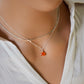 Modeled image. A small, real orange Carnelian stone teardrop pendant suspended from a sterling silver cable chain. This necklace is handmade and also comes in 14k gold filled. The crystal is faceted and varies in shades of orange to red.