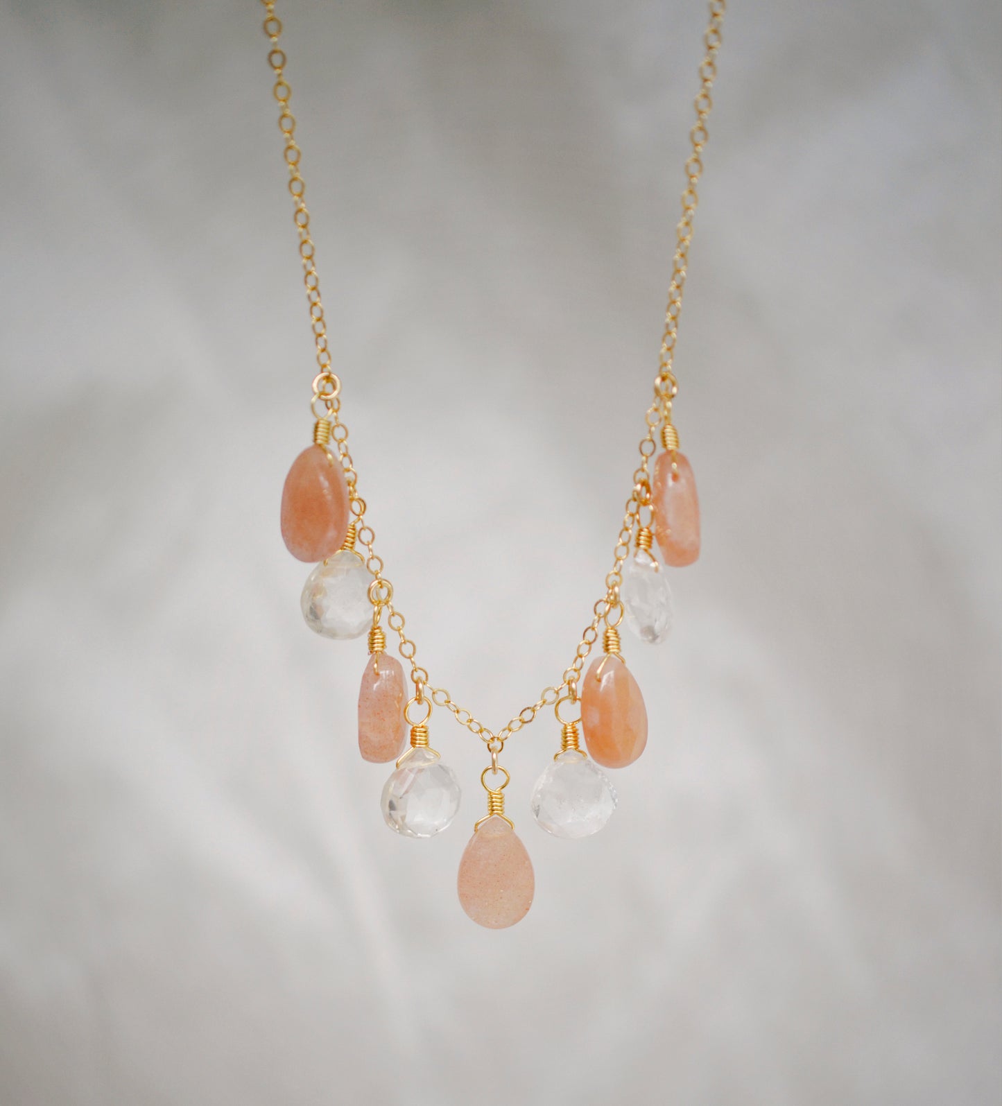 Orange, peach moonstone and clear Crystal Quartz teardrops dangle off a 14k gold filled chain. 