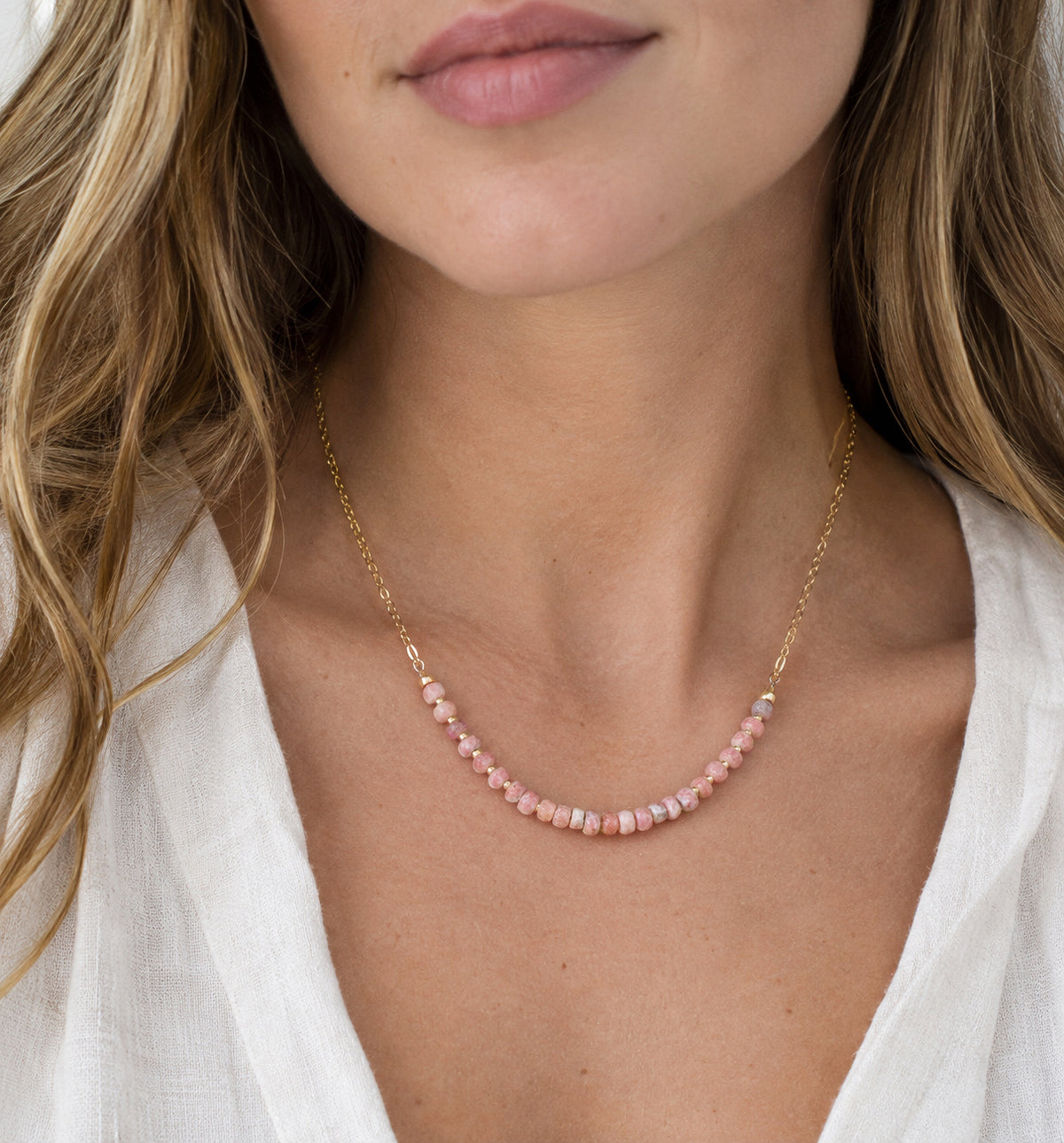 A modeled image of a beaded pink rhodochrosite necklace in 14k gold filled. The stones are natural and faceted and vary in shades of pink, including white and gray. Handmade in Connecticut by Gemnia.