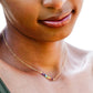 This necklace features natural crystal gemstones set in the order of the rainbow on a dainty bar and chain necklace. It is handmade by GEMNIA Jewelry in Connecticut. Modeled in 14k gold filled.