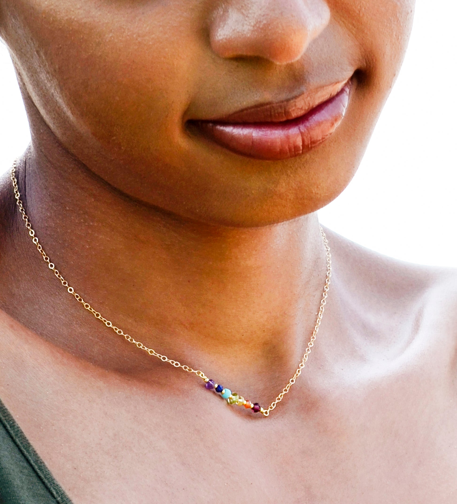This necklace features natural crystal gemstones set in the order of the rainbow on a dainty bar and chain necklace. It is handmade by GEMNIA Jewelry in Connecticut. Modeled in 14k gold filled.