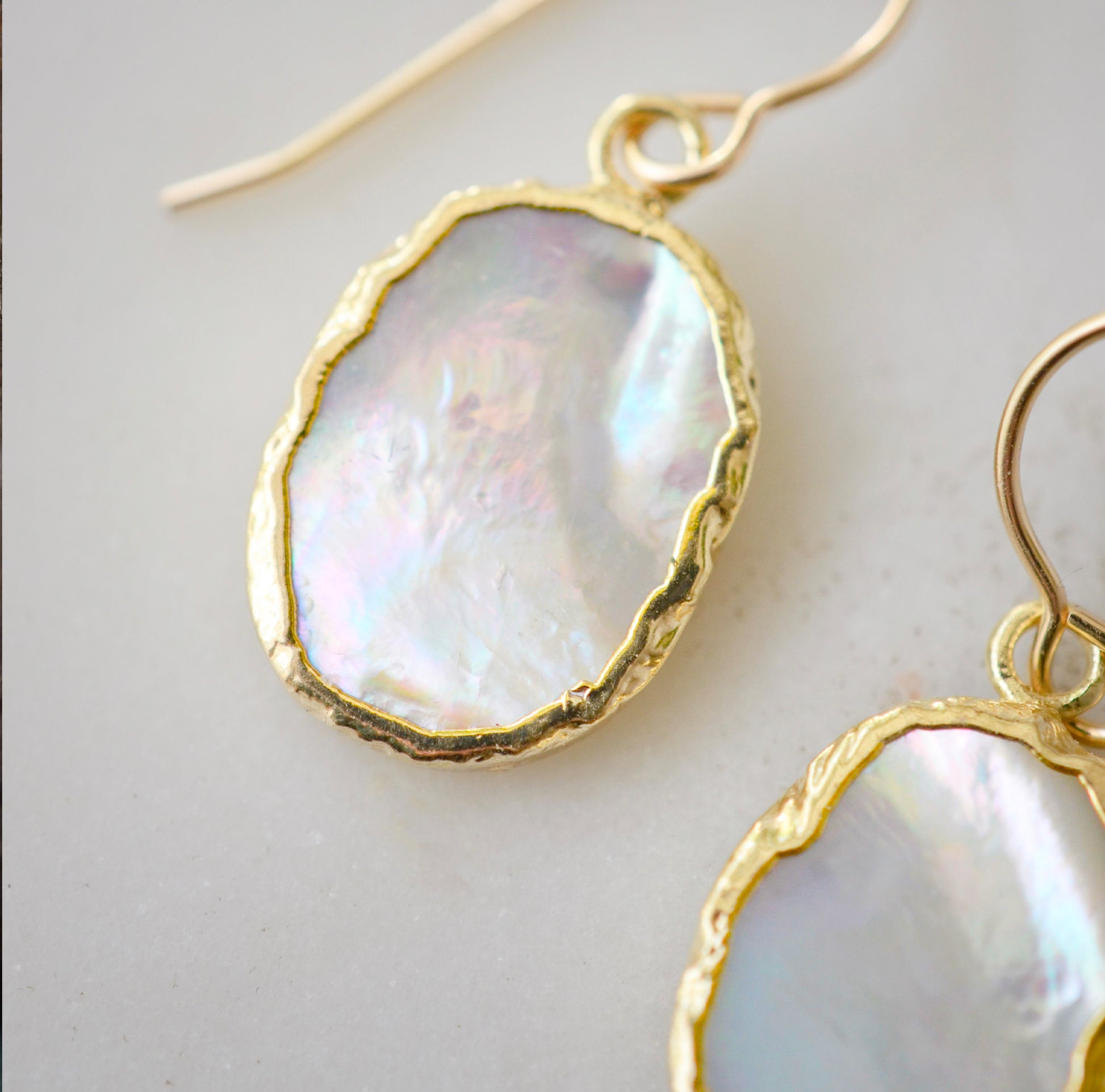 Close up of the shifting colors in these natural white mother of pearl dangle earrings.