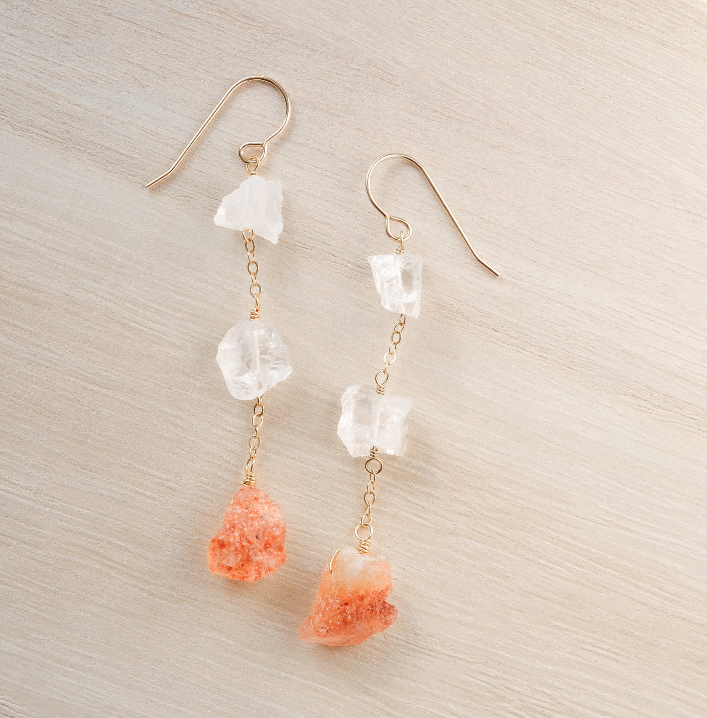 Raw crystal and sunstone earrings. Two clear crystal quartz raw stones are set atop raw, natural sunstone gemstones.