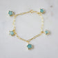 Gold bracelet with blue amazonite star-shaped gemstone charms on a light gray background.