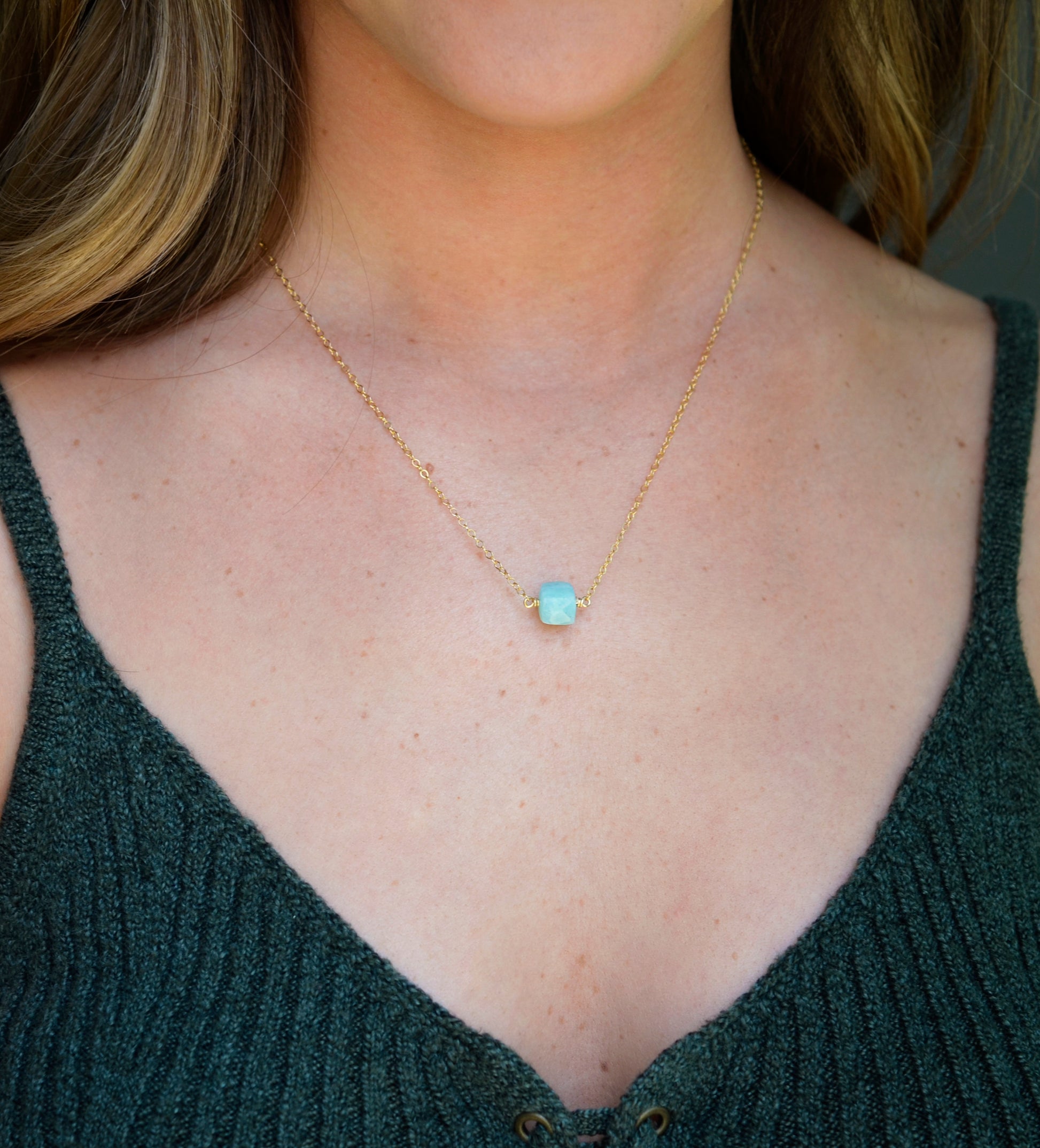 Genuine aqua blue Amazonite gemstone cut into a faceted cube and suspended on a gold filled cable chain. Modeled Image.