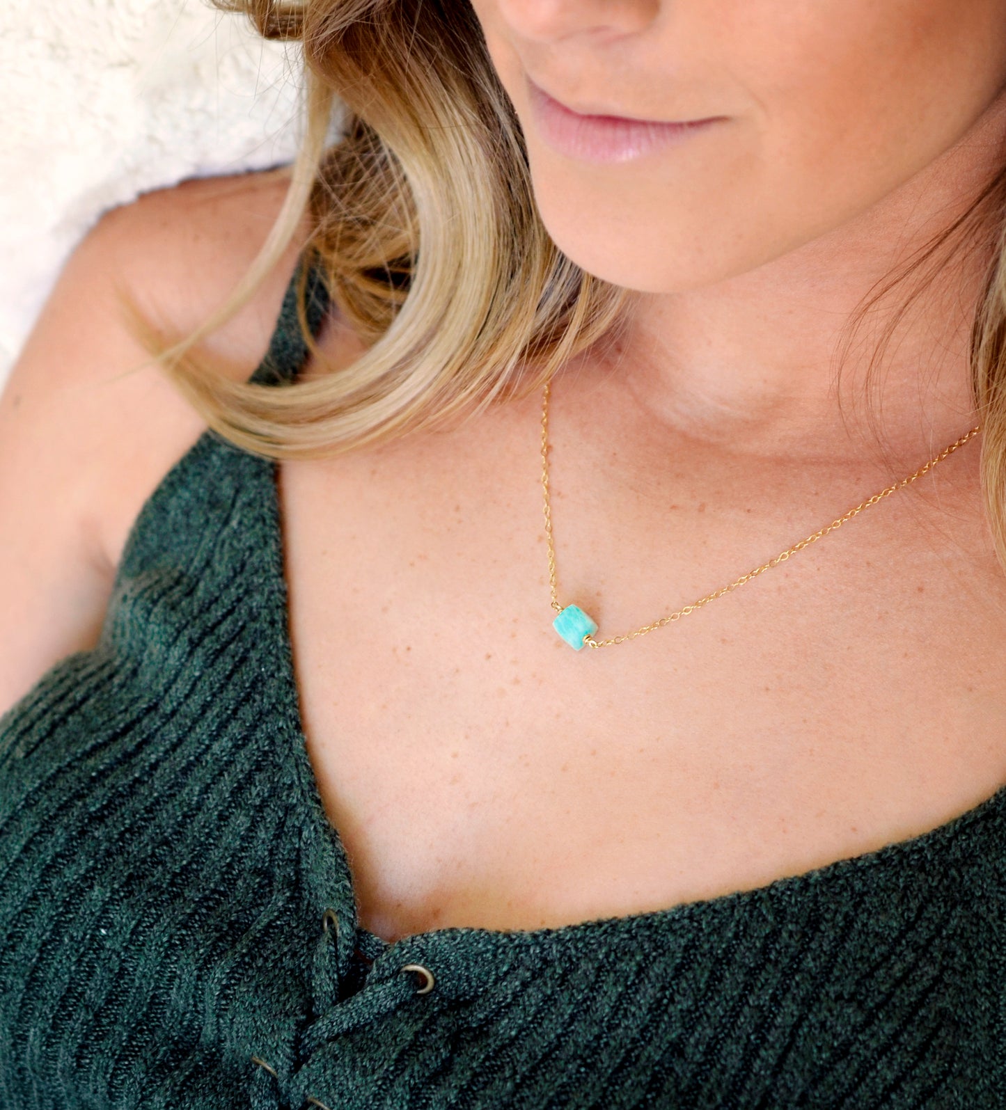 Genuine aqua blue Amazonite gemstone cut into a faceted cube and suspended on a gold filled glittering chain. Modeled Image.