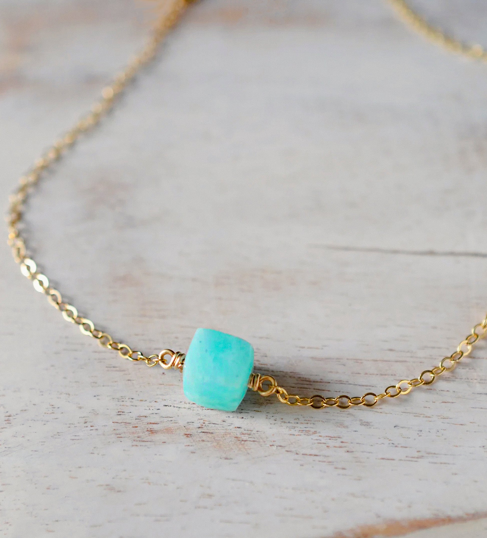 Genuine aqua blue Amazonite gemstone cut into a faceted cube and suspended on a gold filled cable chain. Close Up.