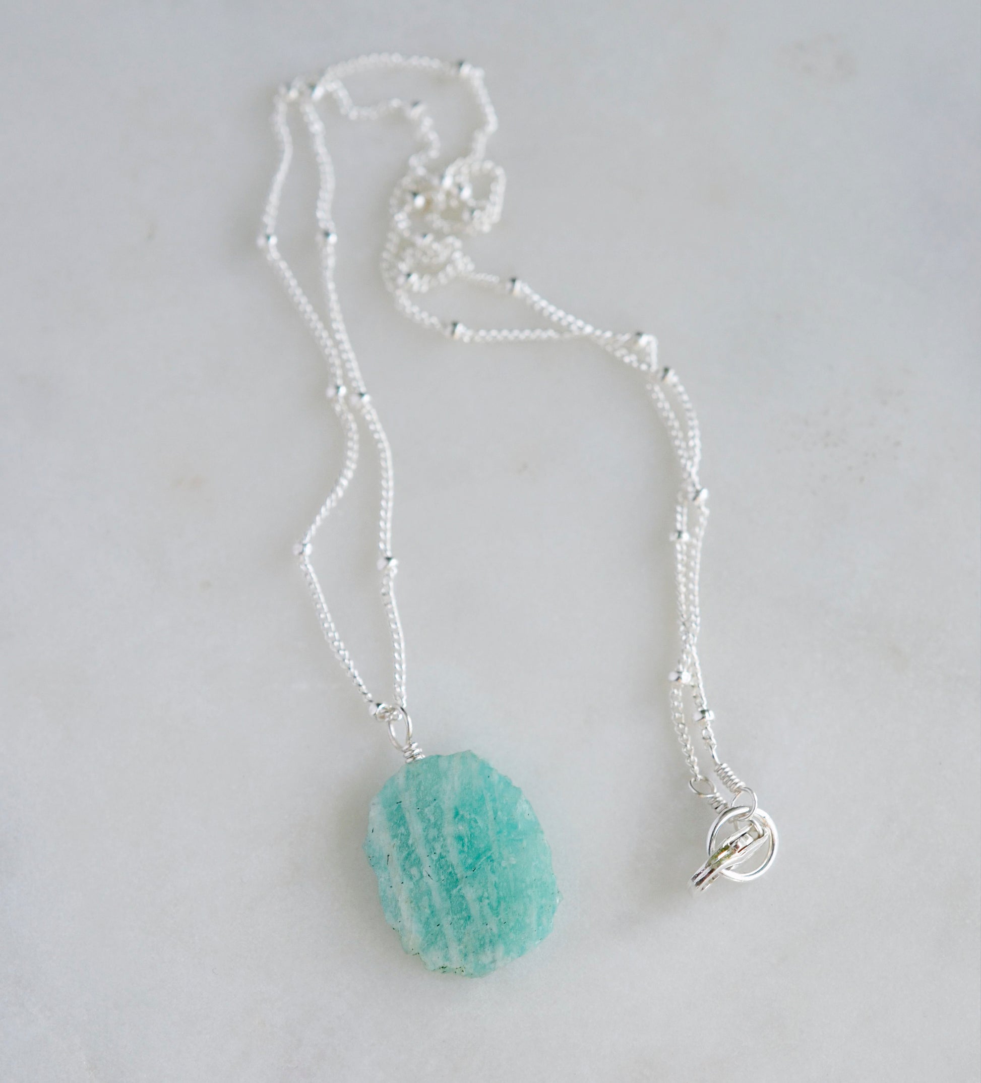 Bright aqua blue Amazonite stone cut into a thin, polished slice with raw edges, then set onto a sterling silver beaded chain.