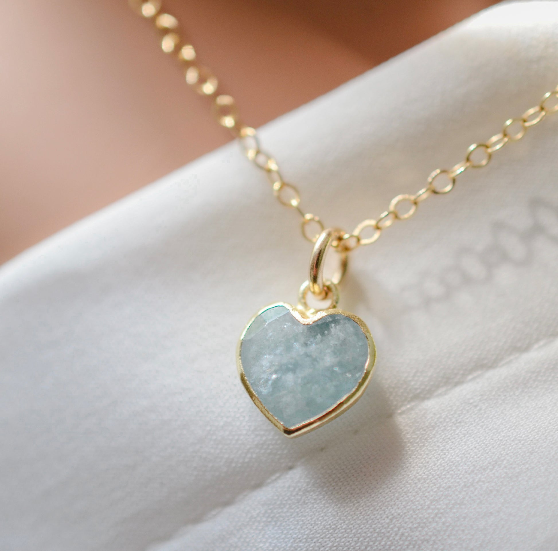 Pale blue natural aquamarine gemstone heart pendant set on a 14k gold filled chain. The stone is genuine and faceted with a 22k gold electroplate bezel.