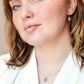 A woman wearing a matching genuine blue aquamarine crystal necklace and earring set. Handmade minimalist stone jewelry by Gemnia.