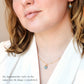 Close-up of a person wearing an aquamarine necklace and earrings with a neutral background.