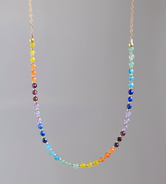 Rainbow chakra gemstone necklace. Crystals are beaded together in this pattern: yellow, orange, red, purple, blue, aqua, green. The gold style is shown.