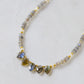 A close up of a handmade, beaded labradorite and pearl dainty necklace in gold. 
