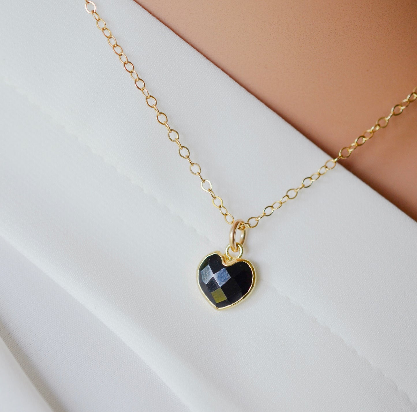 Black onyx heart pendant set on a 14k gold filled chain necklace. The crystal is faceted.