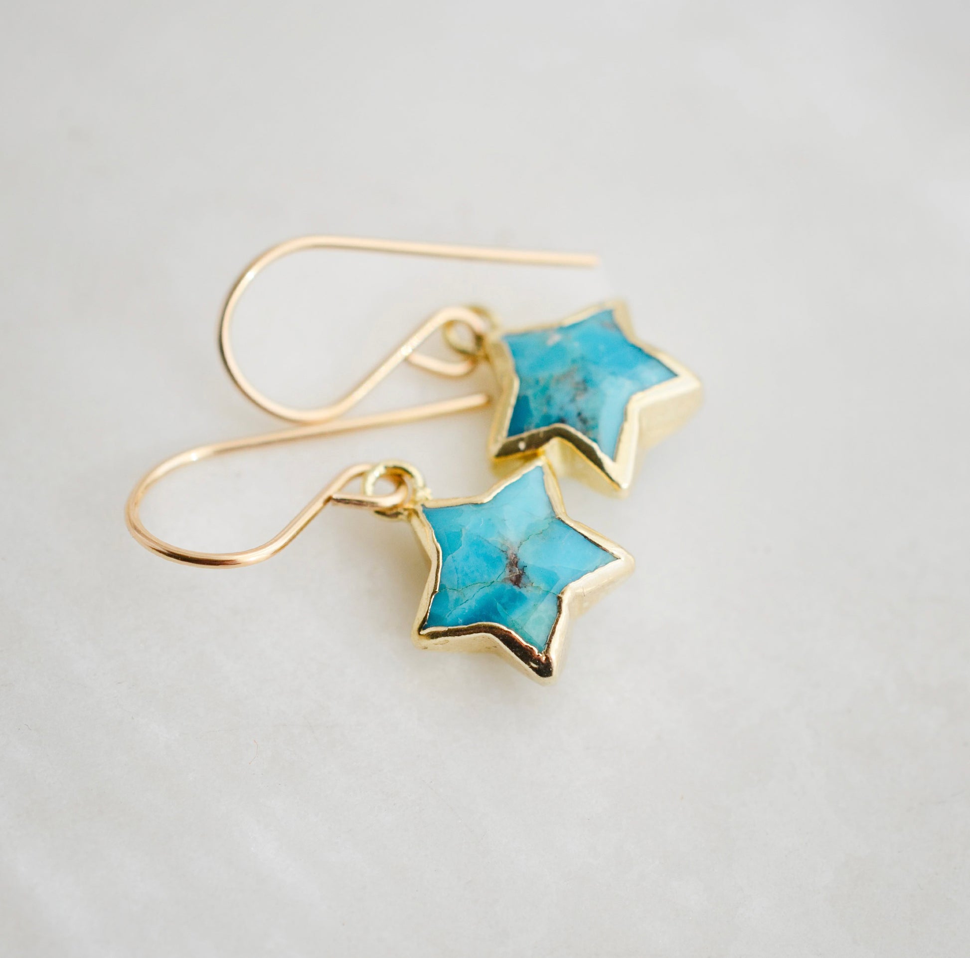 Side view. Minimalist celestial star earrings with turquoise stones set in gold. These dangles are handmade by Gemnia Jewelry in New england.