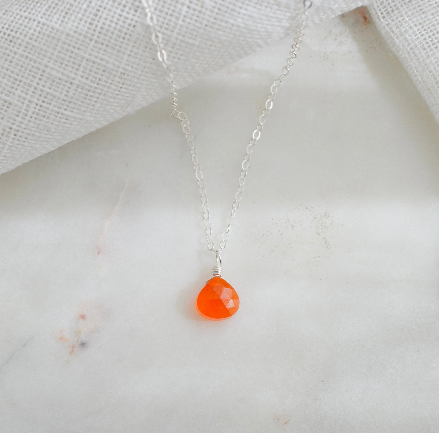 A dainty, real orange Carnelian gemstone teardrop pendant suspended from a sterling silver cable chain. This necklace is handmade and also comes in 14k gold filled.