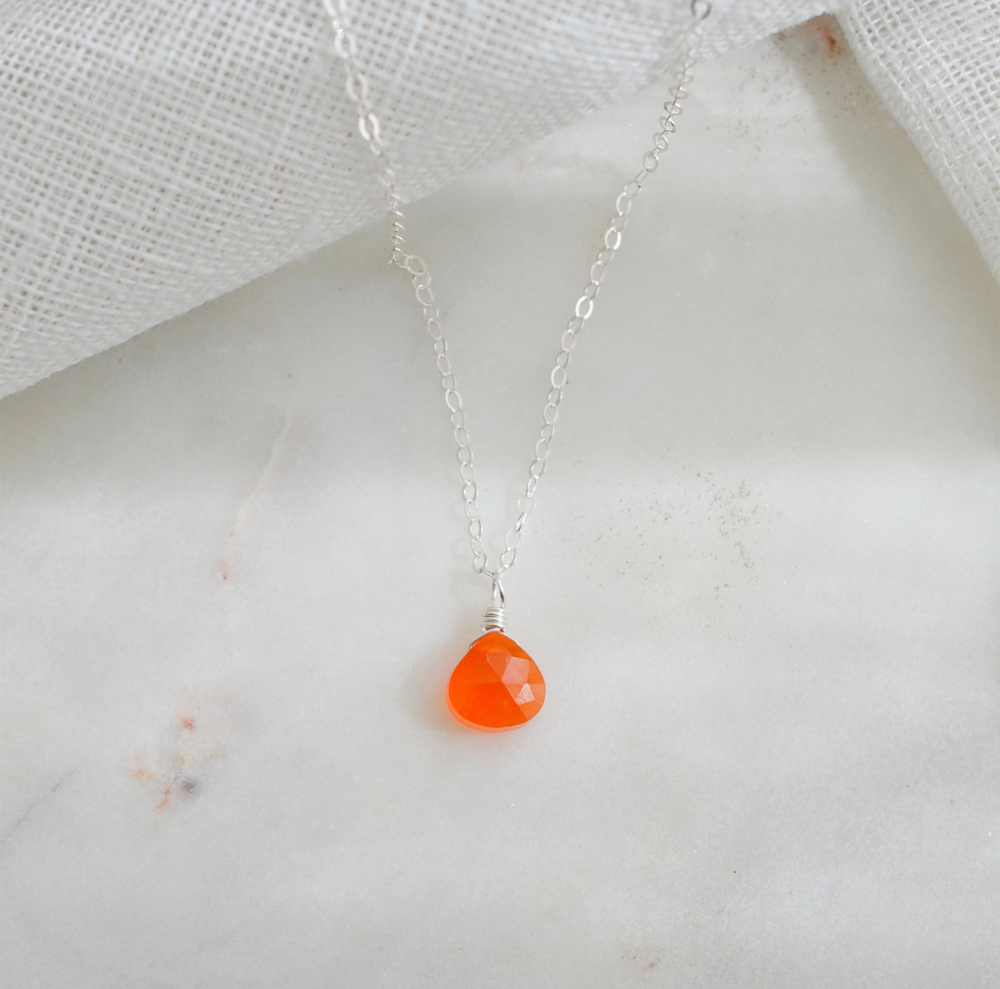 A dainty, real orange Carnelian gemstone teardrop pendant suspended from a sterling silver cable chain. This necklace is handmade and also comes in 14k gold filled.