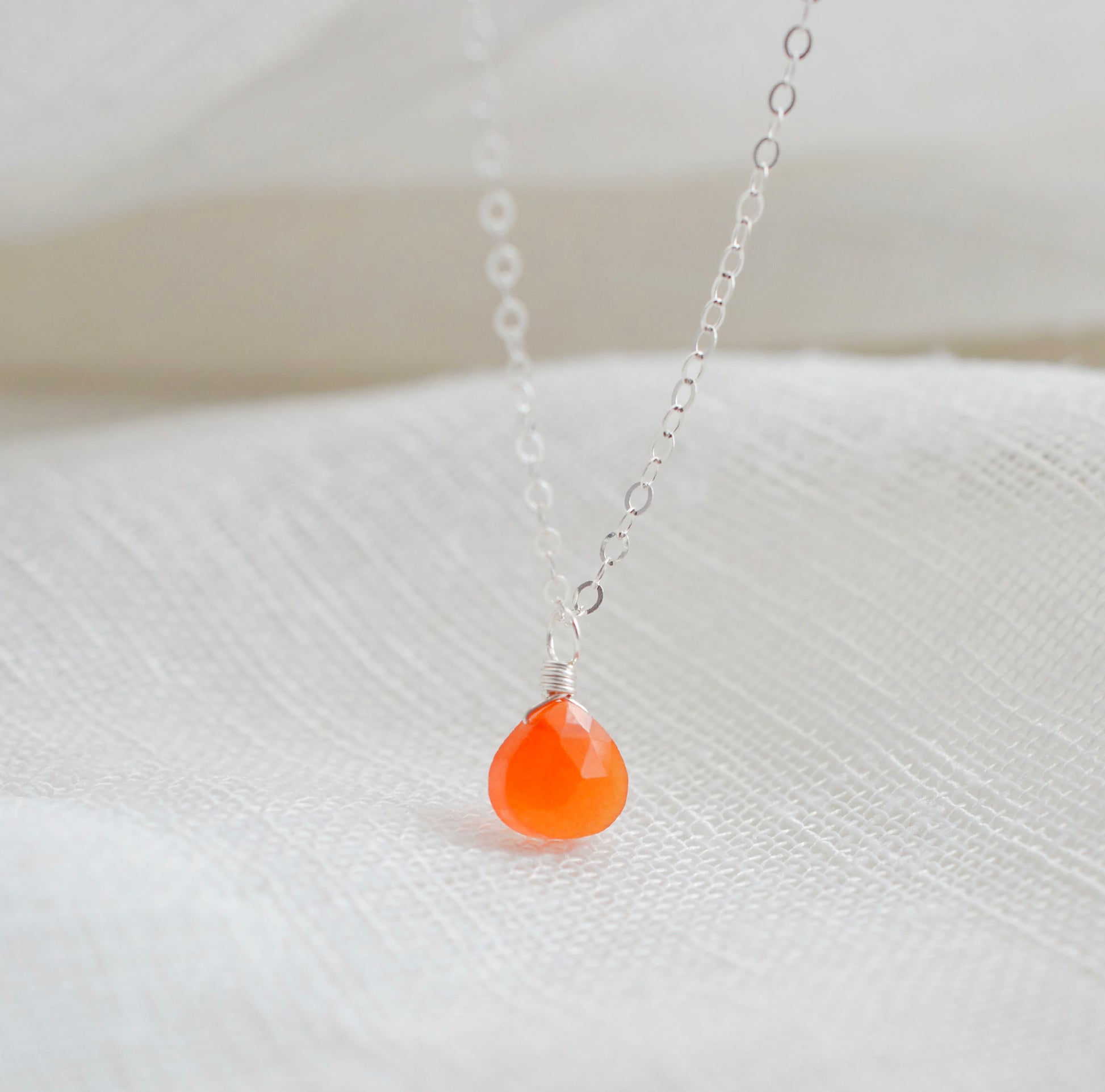 A real, real orange Carnelian stone teardrop pendant suspended from a sterling silver cable chain. This necklace is handmade and also comes in 14k gold filled. The crystal is faceted and varies in shades of orange to red.