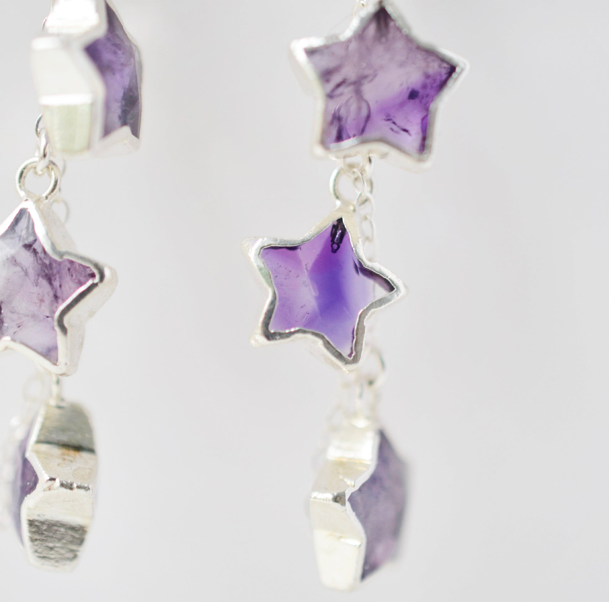 Sterling silver celestial amethyst star earring jewelry. Each earring features three purple amethyst stars dangling from a sterling silver chain.