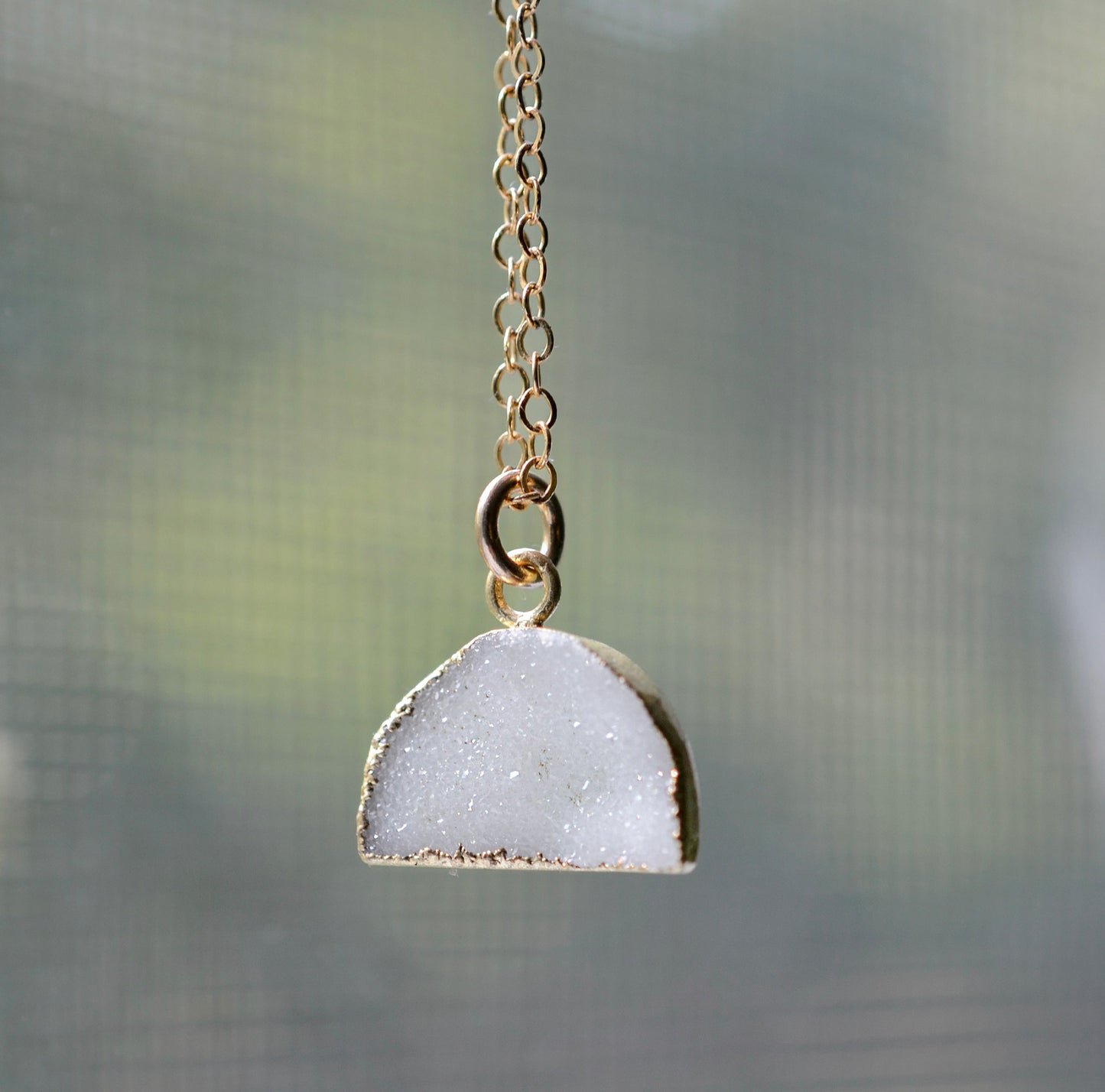 This necklace is handmade with a natural white druzy quartz pendant in a half-circle or crescent shape. Available in 14k gold filled.