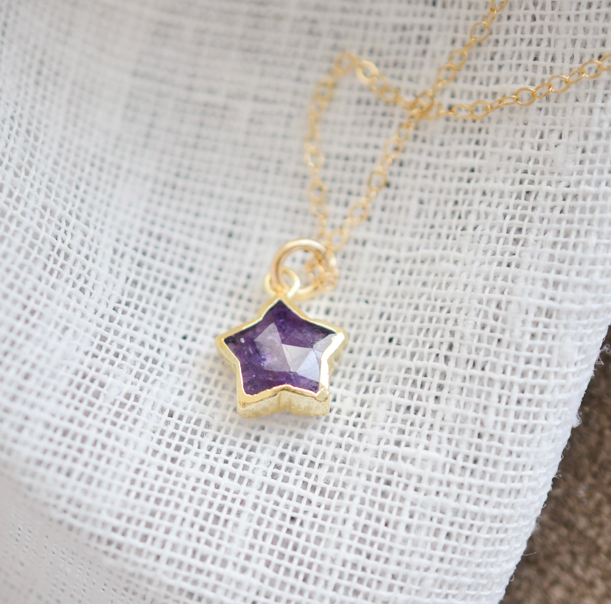 Handmade genuine purple amethyst star pendant set on a 14k gold filled chain. The stone is shown on its side. The bezel is only on the edges of the stone.