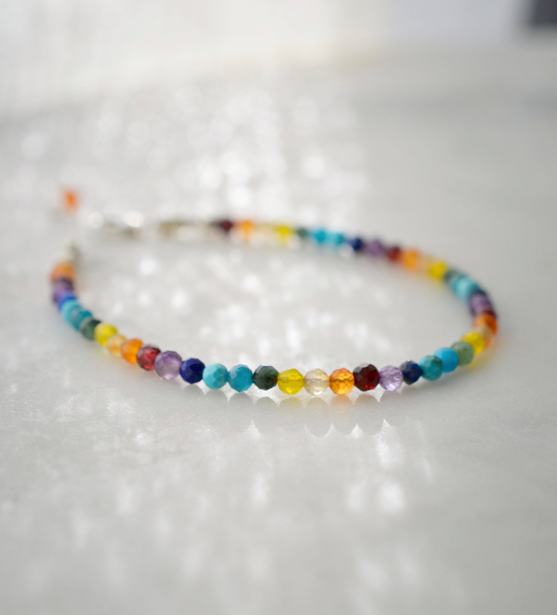 Tiny gemstone beaded bracelet in rainbow colors. Colors include: blue, green, yellow, red, orange, and purple. This bracelet is handmade in Connecticut by Gemnia Jewelry.