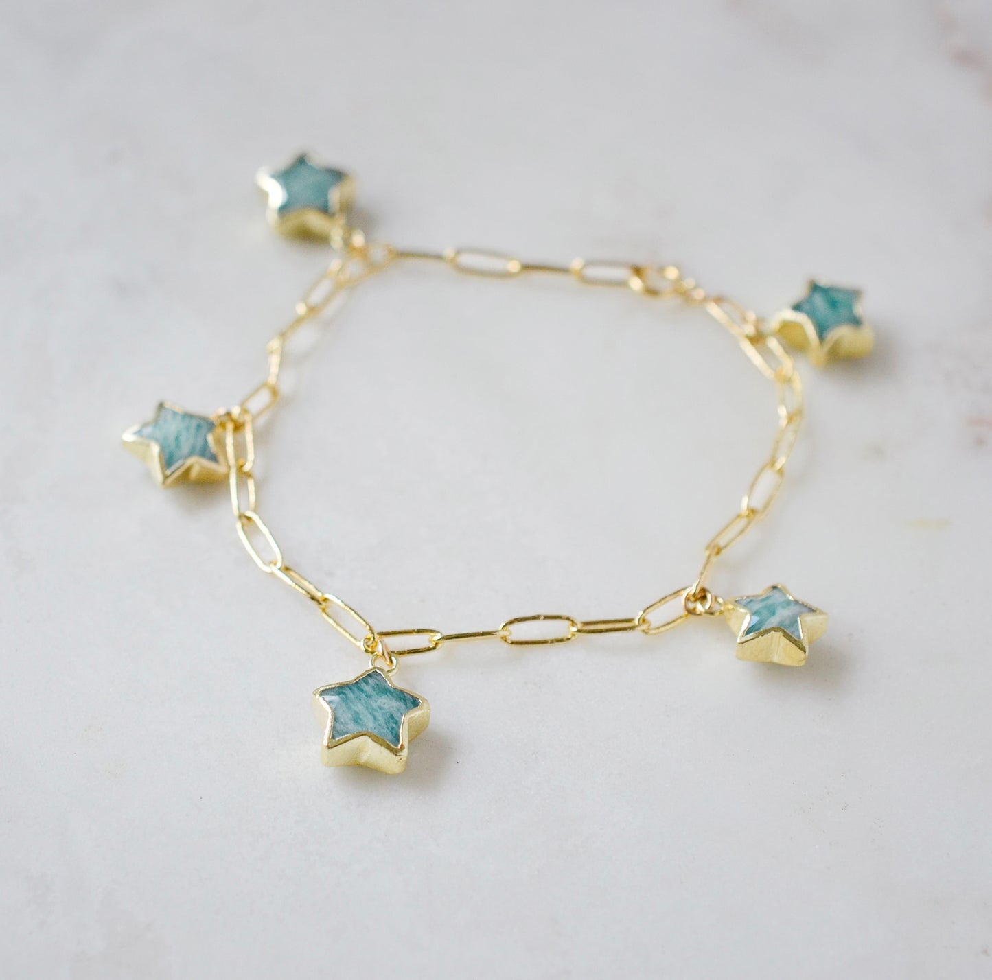A handmade gold bracelet with blue Amazonite star-shaped charms on paperclip chain. Wear it solo or stack it with others. It makes the perfect gift for astrologists, astronomers, and star gazers.