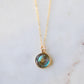 A doughnut shaped natural labradorite round pendant set in gold. The dainty chain is 14k gold filled. The jewelry is handmade in Connecticut by GEMNIA.