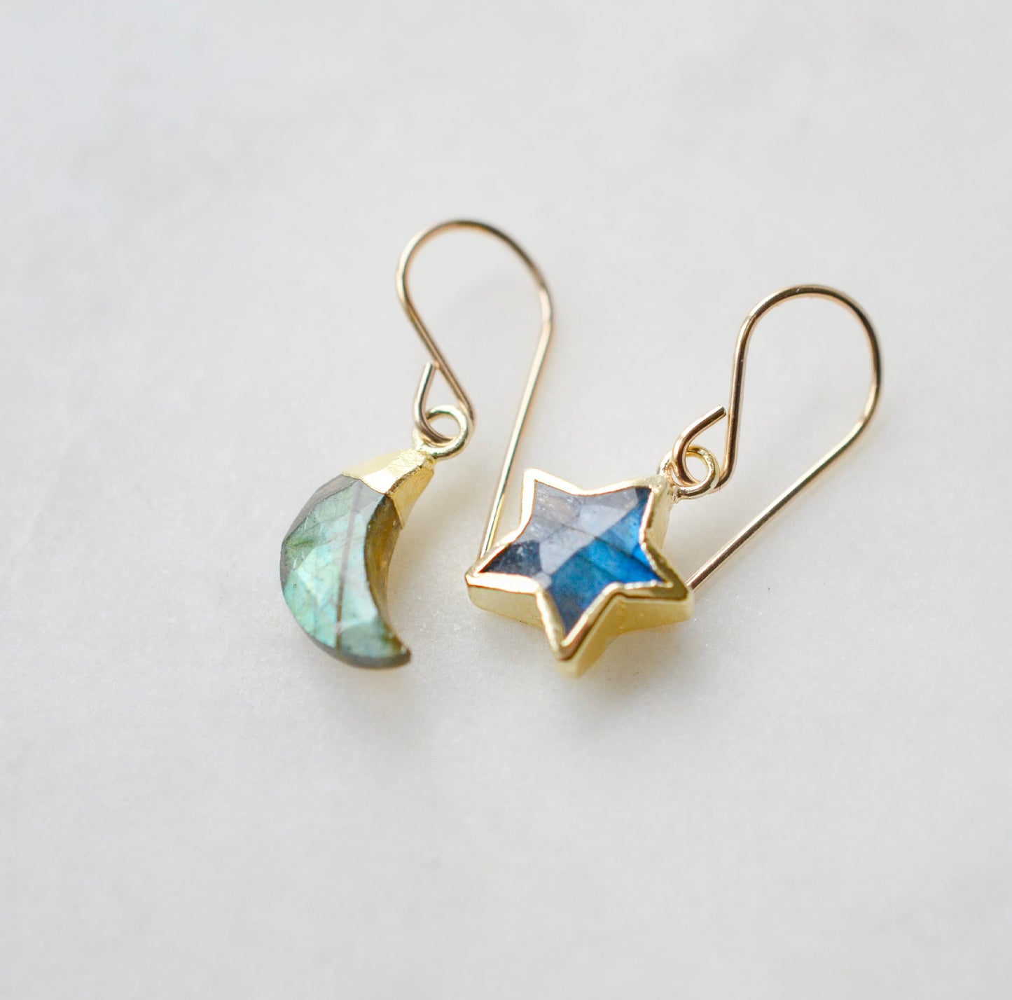 Labradorite Moon and Star earrings. One dangle is a faceted crescent moon, while the other is a star. The stones are naturally gray in color, but shift blue or green with movement. Available in gold or silver.