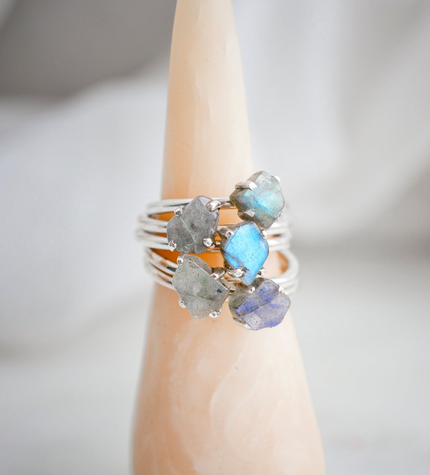 Group image of raw slices of labradorite crystals set onto sterling silver rings. Image shows five rings.