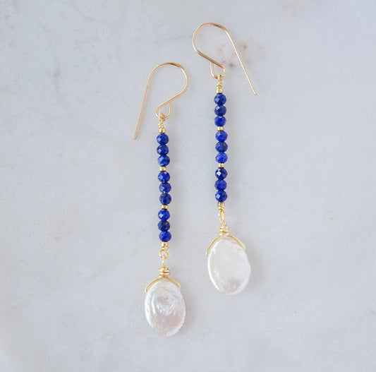 Natural blue lapis lazuli gemstone and white freshwater pearl long dangle earrings. The dangles are long and thin with oval freshwater pearls at the end. They come in 14k gold filled and sterling silver.