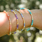Handmade beaded gemstone crystal bracelet in gold filled or sterling silver. These bracelets feature a gemstone of your choice on a bracelet that can be stacked with others or worn alone. Modeled image showing: turquoise, tanzanite, amethyst, and sunstone.