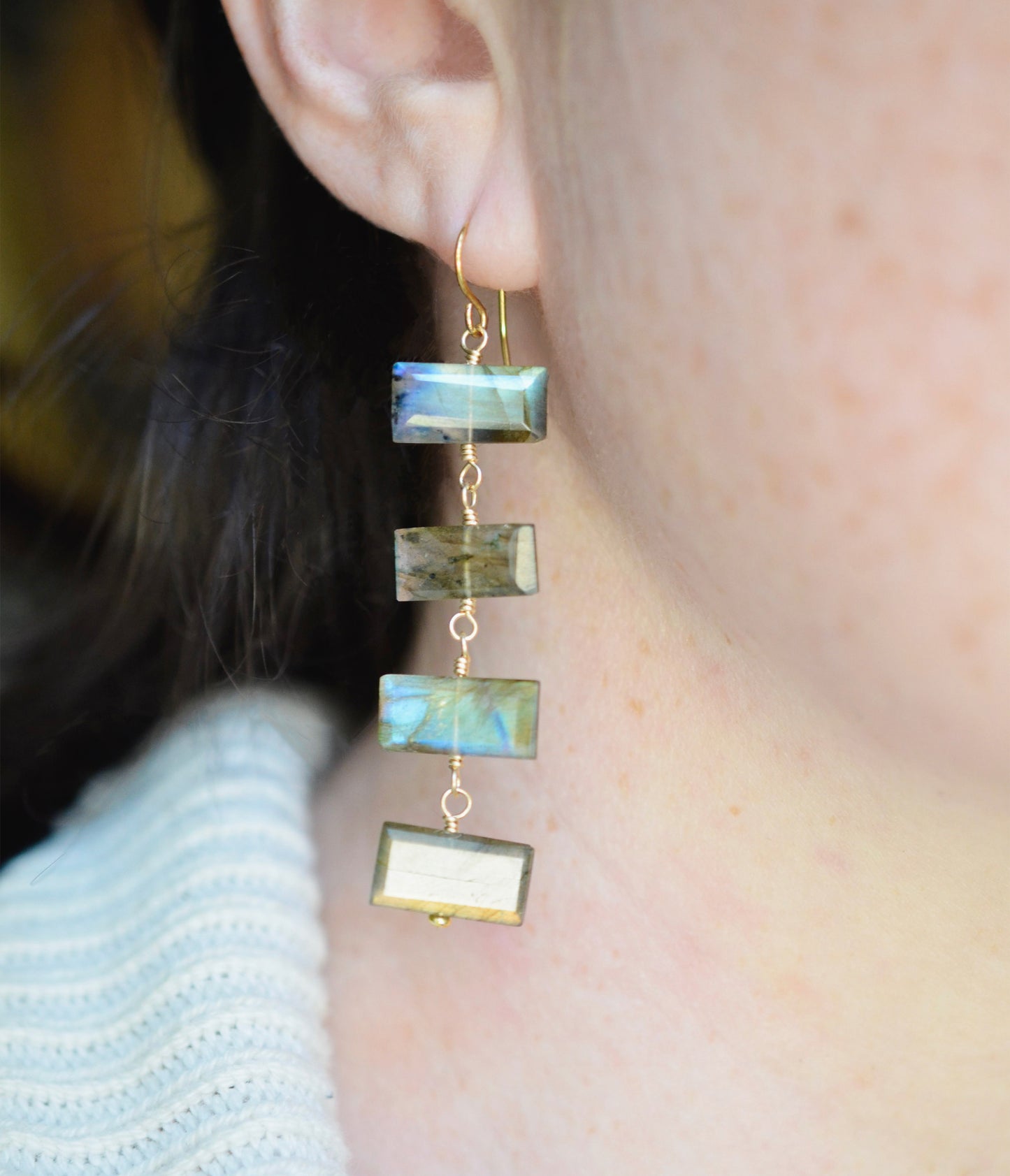 Modeled image: Four faceted emerald cut labradorite gemstones dangle in these 14k gold filled earrings. Each stone flashes blue or green.