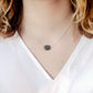 Genuine raw black sunstone gemstone set on a sterling silver chain. The shape of the stone is irregular. Modeled image.