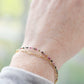 Tiny mulit-color Tourmaline faceted round gemstones on a gold beaded bracelet. Modeled image.