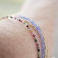 Tiny mulit-color Tourmaline faceted round gemstones on a gold beaded bracelet. Modeled image.