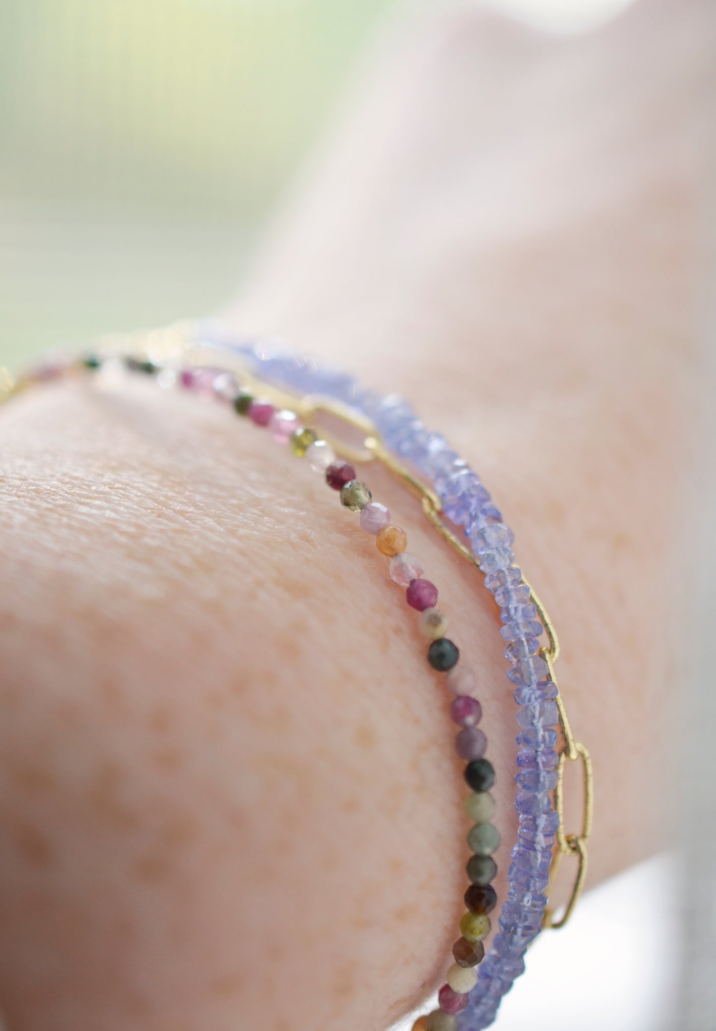 Tiny mulit-color Tourmaline faceted round gemstones on a gold beaded bracelet. Modeled image.