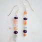 Mismatched gemstone long bar earrings shown in sterling silver. Stones include: amethyst, aquamarine, fluorite, and sunstone. Stones are set onto a long straight bar.